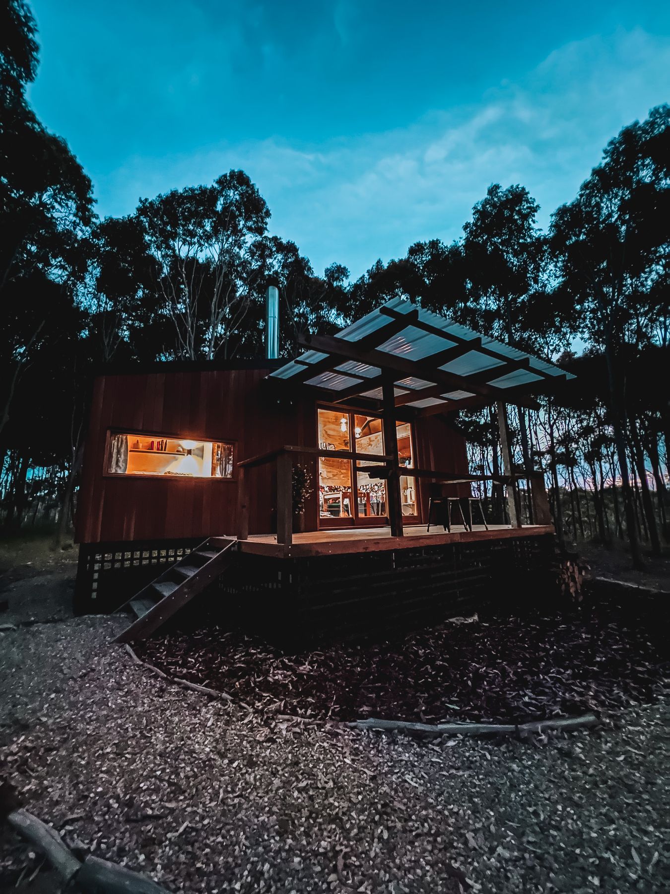 A timber cabin glowing at dusk in the bush