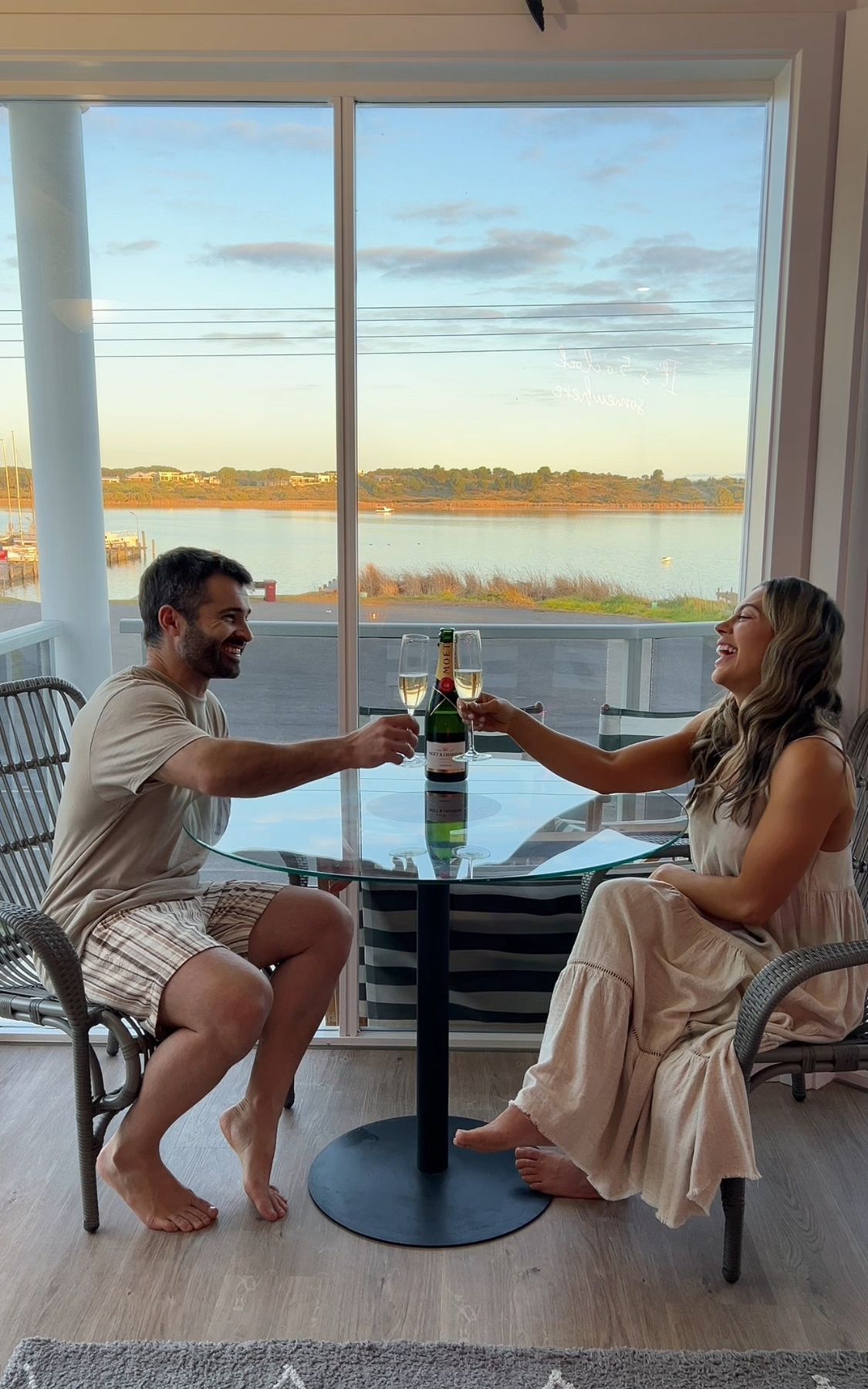A couple toasting at sunset with a water view